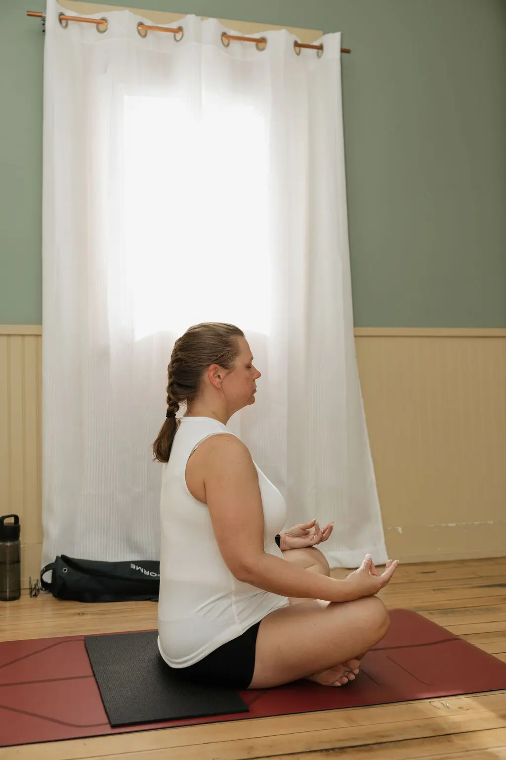 Woman meditating in a quiet room with natural light.